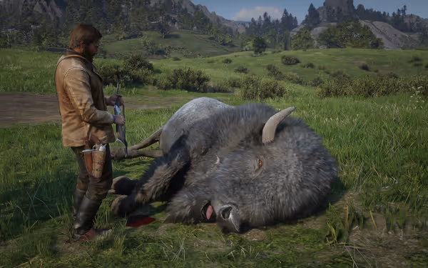 A man standing next to a large bison lying on the grass in an open field.