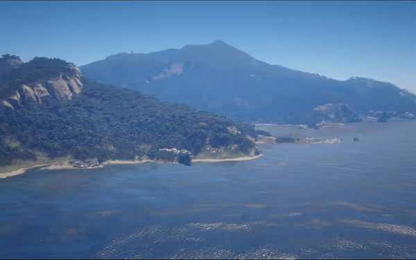 Coastal landscape with green hills and a blue ocean under a clear sky.
