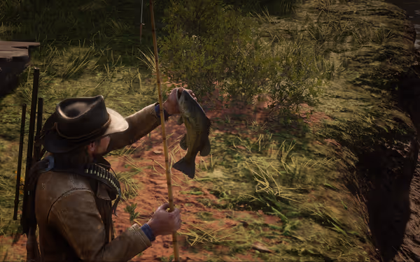 Person holding fish, using fishing rod near grassy riverbank.