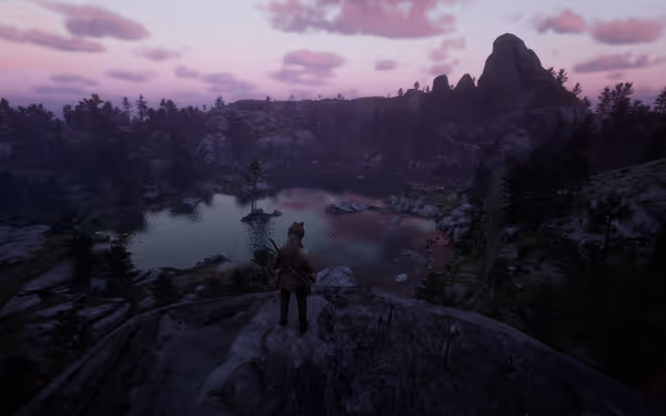 Person on cliff overlooking lake, trees, and mountains at dusk.