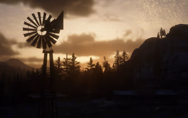 A windmill stands against a sunset sky, overlooking trees and distant hills.