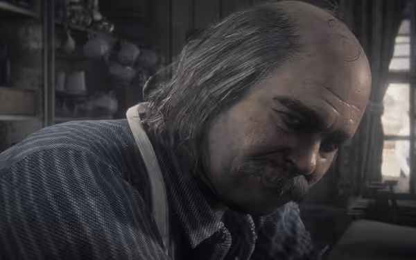 A bald man with a mustache looks thoughtfully, surrounded by shelves and light.