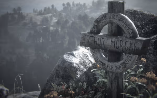 A wooden grave marker written "Arthur Morgan" surrounded by flowers, overlooking distant hills.