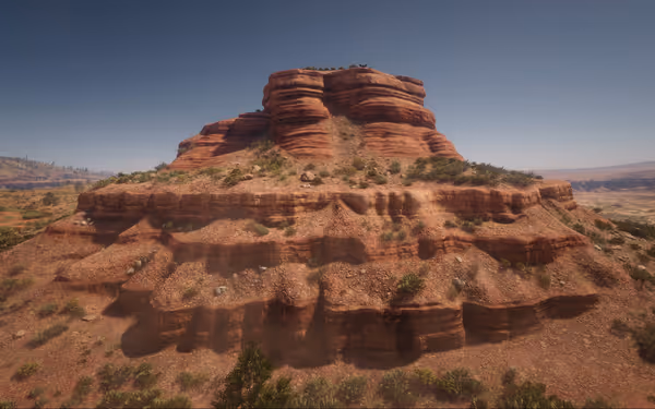 A large red rock mesa with layered formations surrounded by sparse vegetation.