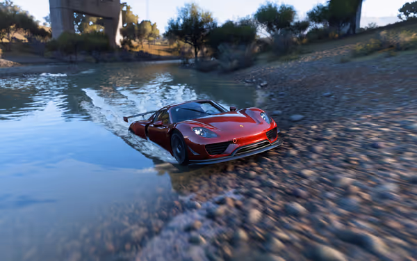 A red sports car driving out of a river at high speeds, leaving a wake