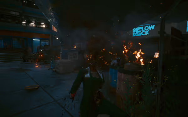 A headless body in a green suit kneels amid fire, smoke, and urban destruction