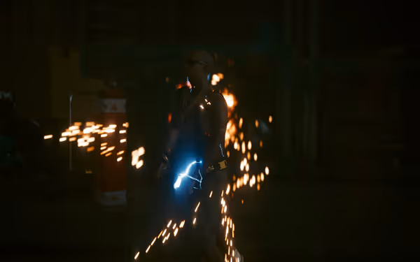 A heavily tattooed man in sunglasses is struck by electricity amid flying sparks