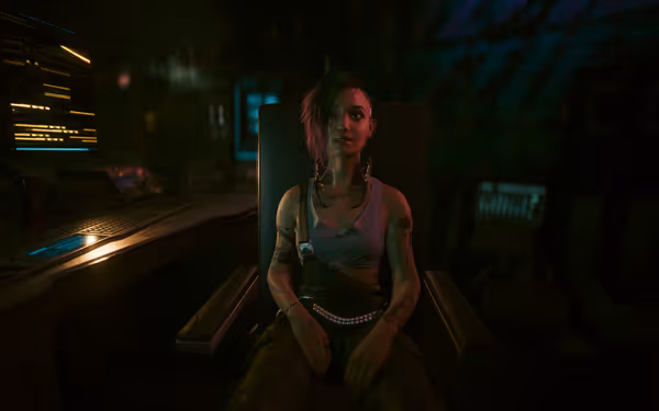 A woman with tattoos, cybernetic neck implants, and asymmetrical hair sits in a dimly lit tech-filled room.