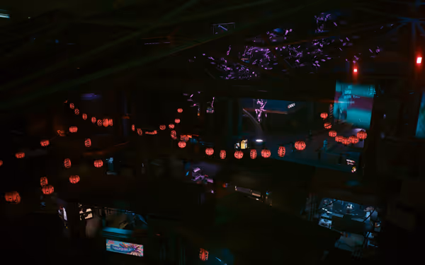 Red lanterns hang above a dark urban market with glowing signs and scattered people.