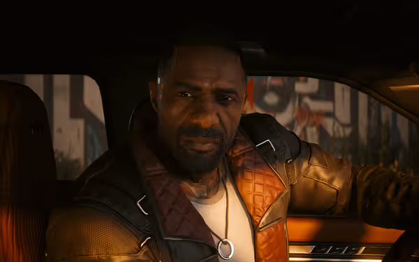 A serious-looking man with cybernetic implants sits in a car wearing a leather jacket.