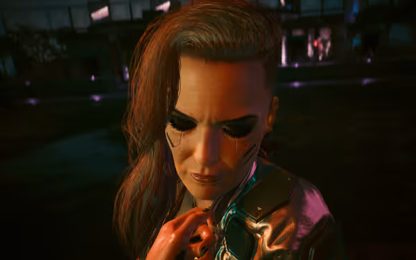 A woman with side-shaved hair and facial implants looks down with a solemn expression.