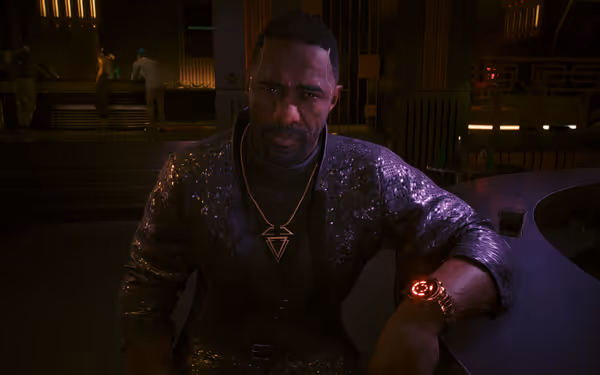 A man in a sequinned suit sits at a purple lit bar.