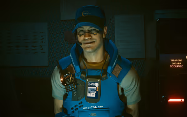 A smiling man in blue Orbital Air uniform stands beside an occupied weapons locker.