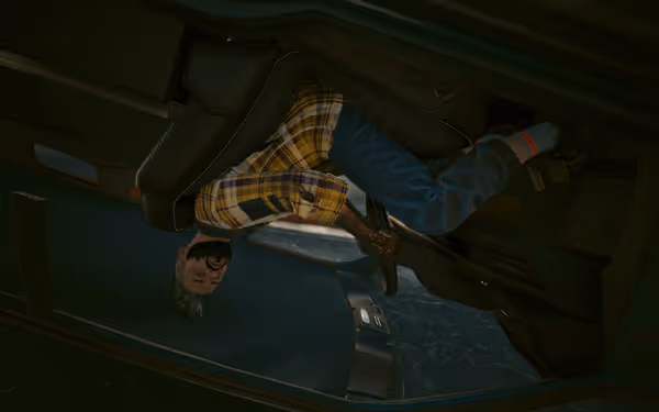 Man in yellow plaid shirt sits upside down in a flipped car.