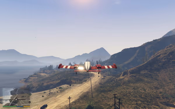 A red and white aircraft flies low over a mountainous landscape with ocean in the background.