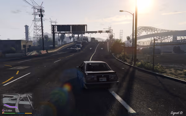 A car drives up a hill with a bridge in the background and sun glare.