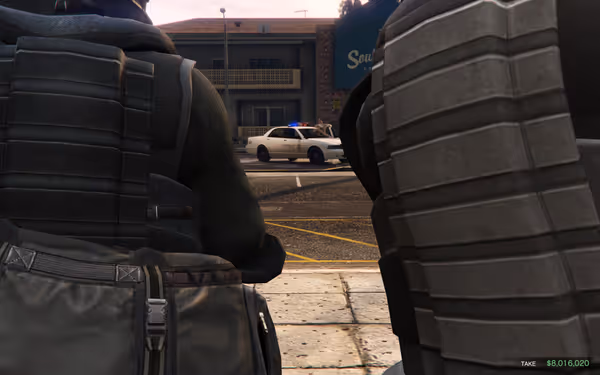Two armored figures observe a police car in the distance, one is holding a large bag.