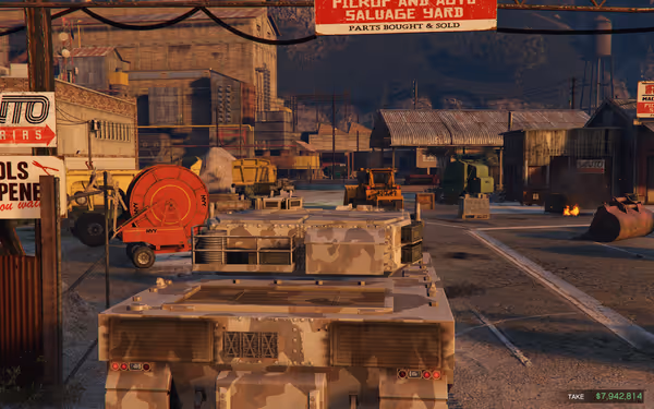 A camouflage armored vehicle sits in a busy salvage yard with machinery and industrial buildings.