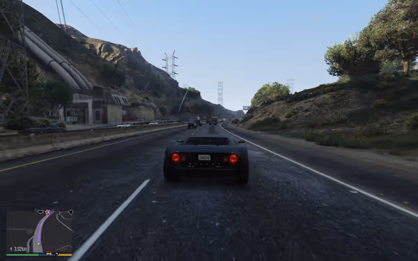 A black sports car drives down a multi-lane highway surrounded by hills, other vehicles ahead.