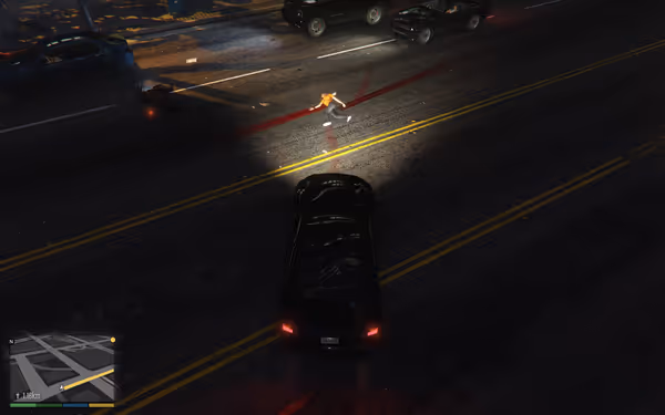 A person lies injured in the road at night, with a car and motorcycle nearby.