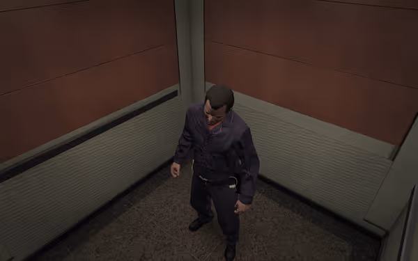 A man in a dark jumpsuit stands alone in a small, dimly lit elevator.