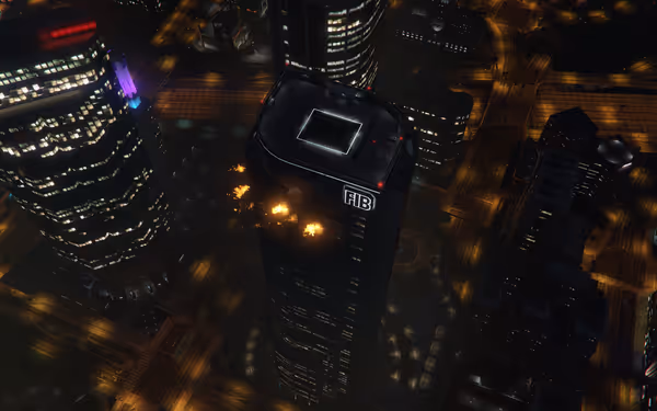 A tall building with "FIB" on it is on fire amid city lights at night.