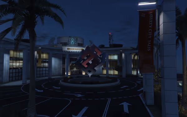 A nighttime office complex features a floating red and black cube sculpture surrounded by palm trees.