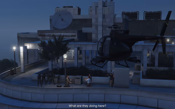 A black helicopter hovers outside a building at night as armed guards and men gather below.