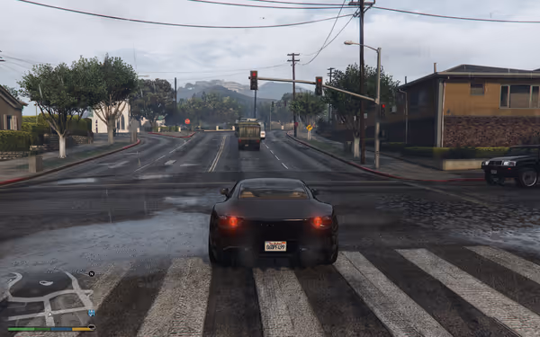 A black sports car waits at a rainy intersection with a red light and wet roads.