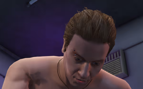 A shirtless man with short hair and facial piercings looks downward indoors.