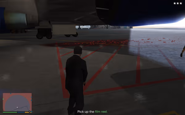 A man in a suit stands under a jet wing inside an airport hangar.