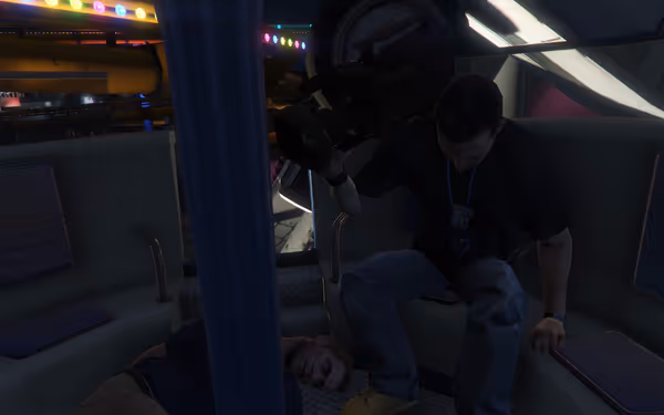 A man holds a video camera inside a cabin, with another person lying on the floor.