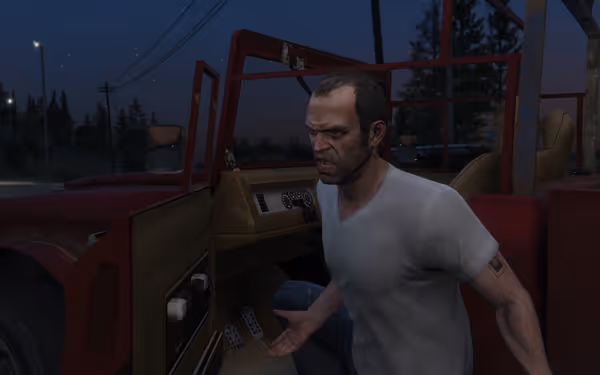 A man with a distressed expression stands inside a red, damaged vehicle at dusk.