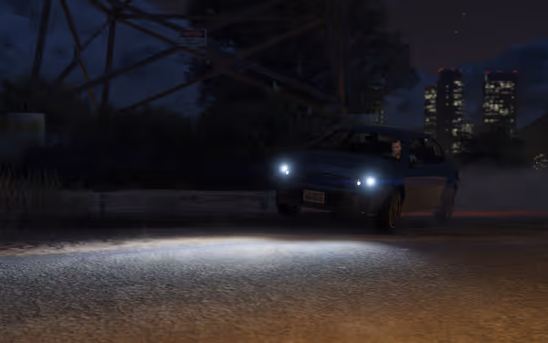 A small blue car with headlights on drifts near power lines under a night sky.