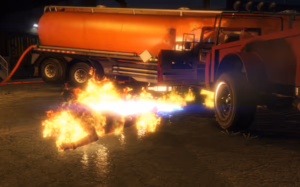 A person engulfed in flames crawls on the ground near a large orange fuel truck.