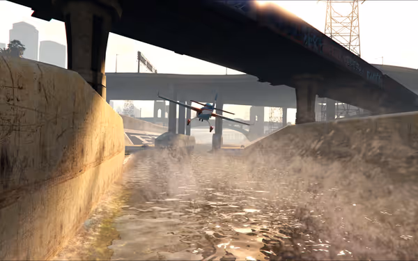 A small plane flies close to the water under a city bridge in a concrete channel.
