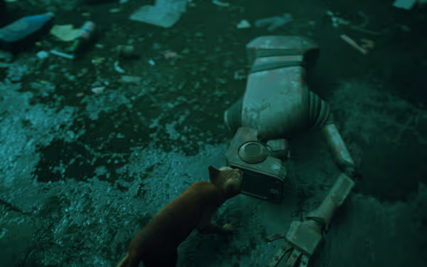A small orange cat examines a broken robot lying on a dirty floor.