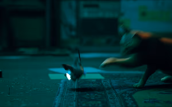 An orange cat swiftly swipes at a small flying robot in a dim room.